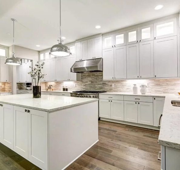 A pristine kitchen with white cabinets and wooden floors